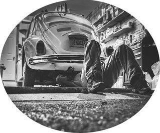 Mechaniker arbeitet unter einem VW Käfer